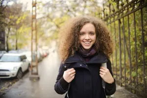 A cheerful young woman with curly hair walks on an urban street in autumn. jigsaw puzzle