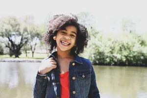 A cheerful girl with curly hair smiling outdoors by a lake. Captured in Texas. jigsaw puzzle