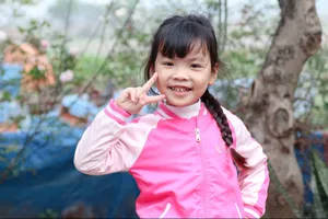 A cheerful young girl in a pink jacket gives a peace sign outdoors. jigsaw puzzle