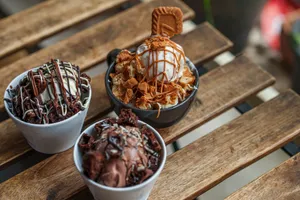 Overhead view of three ice cream desserts with various toppings on a wooden table. jigsaw puzzle