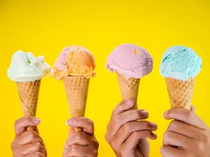Four colorful ice cream cones held up against a bright yellow backdrop, showcasing various flavors. jigsaw puzzle