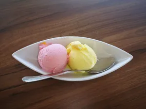 Delicious strawberry and lemon ice cream scoops served in a white bowl with a spoon on wooden table. jigsaw puzzle