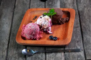 Three artisanal ice cream scoops on a wooden plate with chocolate chips and blueberries. jigsaw puzzle