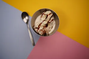 Delicious ice cream in a metal bowl with chocolate drizzle on a vibrant geometric background. jigsaw puzzle