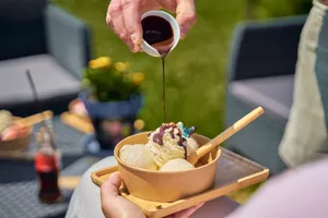 Close-up of chocolate sauce being poured over a bowl of vanilla ice cream outdoors. jigsaw puzzle