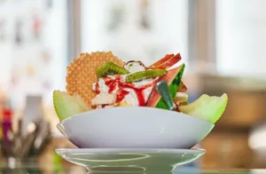 Delicious fruit and ice cream dessert topped with syrup and wafers in a bowl. jigsaw puzzle