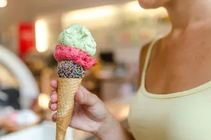 A close-up of a woman holding a delicious ice cream cone with sprinkles indoors. jigsaw puzzle