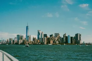 A breathtaking view of New York City's skyline from a river with boats and skyscrapers under a clear blue sky. jigsaw puzzle