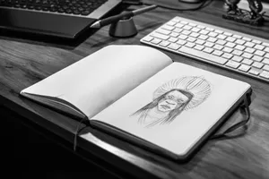 Monochrome image of a sketchbook with a pencil drawing on a wooden desk with laptop and keyboard. jigsaw puzzle