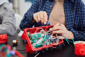Close-up of hands assembling a robotic project with wires and circuits. jigsaw puzzle