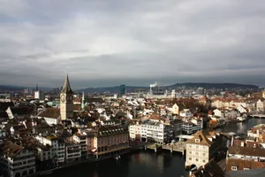 Explore a stunning aerial view of Zurich's historic cityscape with clock towers and canals under a cloudy sky. jigsaw puzzle