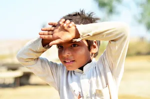 A happy young boy shielded from the sun, enjoying a sunny day outside. jigsaw puzzle