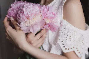 A woman gently holds pink peonies, showcasing beauty and elegance. jigsaw puzzle
