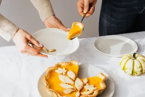 Elegant pumpkin pie slice being served with white plates and decorative gourd on a table. jigsaw puzzle