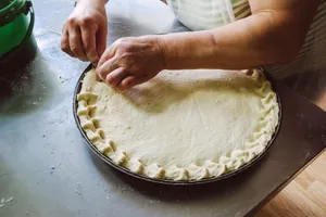 Hands shaping pie dough on a baking tray, showcasing homemade food preparation. jigsaw puzzle