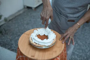 Close-up of hands adding whipped cream to a delicious pumpkin pie on a wooden plate. jigsaw puzzle