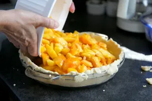 A close-up of a homemade peach pie being filled with fresh fruit. Captures the essence of baking. jigsaw puzzle