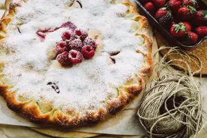 Delicious homemade raspberry pie dusted with powdered sugar, surrounded by fresh strawberries. jigsaw puzzle