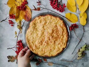 Freshly baked pie surrounded by autumn leaves and rowanberries on a rustic table. jigsaw puzzle