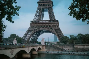 Eiffel Tower and Seine River bridge in Paris at twilight, with evening lights and nearby trees. jigsaw puzzle