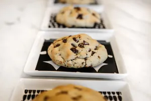 Freshly baked chocolate chip cookies displayed on elegant white plates for a tempting presentation. jigsaw puzzle