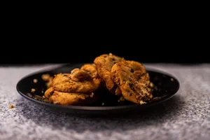 Freshly baked chocolate chip cookies displayed on a black plate in a cozy setting. jigsaw puzzle