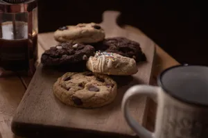 Delicious assorted cookies on a wooden board accompanied by coffee, perfect for a cozy snack time. jigsaw puzzle