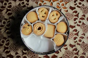Top view of assorted butter cookies in a round tin on a decorative tablecloth. jigsaw puzzle
