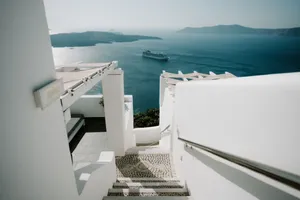 White stairs leading to a stunning view of the sea with a cruise ship near a Greek island. jigsaw puzzle