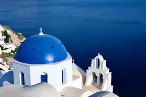 Breathtaking view of Santorini's blue-domed church overlooking the Aegean Sea, capturing Greek architecture. jigsaw puzzle