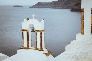 A serene view of a white church bell tower with the Aegean Sea in the background in Santorini, Greece. jigsaw puzzle