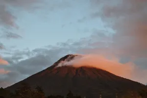 A tranquil mountain scene at dusk with clouds gently hugging the peak. jigsaw puzzle