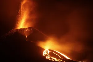 A powerful volcanic eruption at night with flowing lava and sparks creating a dramatic scene. jigsaw puzzle