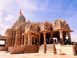 An impressive Hindu temple with detailed carvings and a vibrant flag under a clear blue sky. jigsaw puzzle