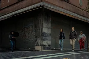 Pedestrians walk past a closed shop on a rainy city street, creating a candid urban scene. jigsaw puzzle