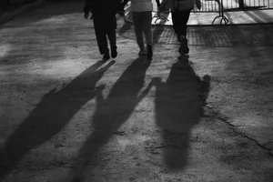 Silhouettes of people walking on a pavement with dramatic shadows during sunset. jigsaw puzzle