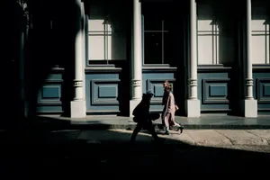 Silhouetted pedestrians walk past ornate architecture on a sunny New York City street. jigsaw puzzle