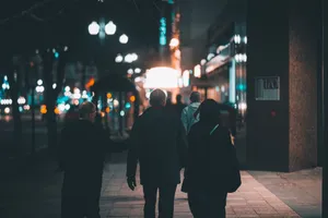 A group of people walking at night on a city sidewalk under streetlights. jigsaw puzzle