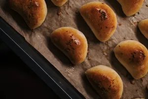 A batch of golden, freshly baked bread rolls with herbs on parchment paper. jigsaw puzzle