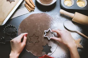 Hands cutting star-shaped cookies from chocolate dough, surrounded by baking tools. jigsaw puzzle