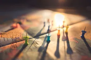 A close-up view of colorful push pins casting shadows on a world map during sunset, highlighting global travel. jigsaw puzzle