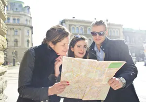 Three tourists exploring a city using a map under bright daylight, enjoying their travel journey. jigsaw puzzle