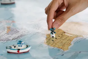 Close-up of a hand placing a tiny windmill on a map, highlighting Australia. jigsaw puzzle