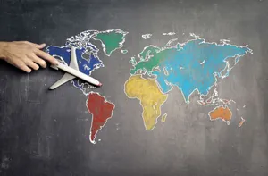 Top view of crop anonymous person holding toy airplane on colorful world map drawn on chalkboard jigsaw puzzle