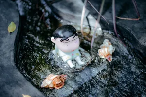 Toy figurine sitting in a water stream among seashells, creating a whimsical scene. jigsaw puzzle