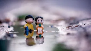 Close-up of two adorable figurines sitting by a water reflection, evoking romance and serenity. jigsaw puzzle