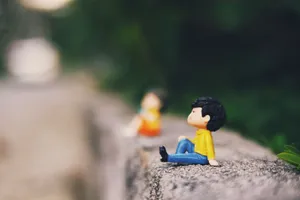 Colorful small couple figurines placed on concrete surface on street with lush green trees on blurred background on summer day jigsaw puzzle