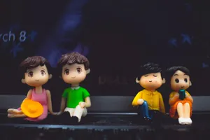 Small plastic statuettes of women near boyfriends in bright apparel with hat and book sitting on portable computer jigsaw puzzle