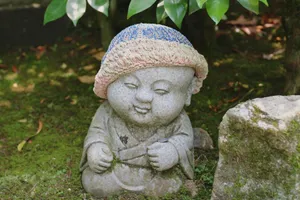 Little Buddha statue with a knitted cap in a serene Japanese garden. jigsaw puzzle