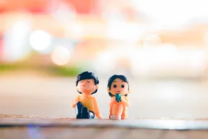 Cute colorful figurines of boy and girl placed on sidewalk on street with glowing lights in city on blurred background jigsaw puzzle
